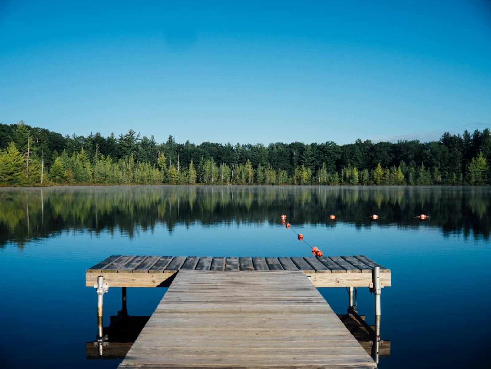A wooden jetty reaching into a calm blue lake