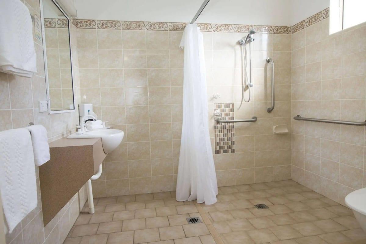 Step-free accessible bathroom with grab rails, roll-under basin and open shower