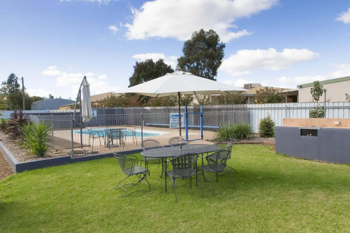 The motel's lawn and outdoor pool with a shaded table under an umbrella