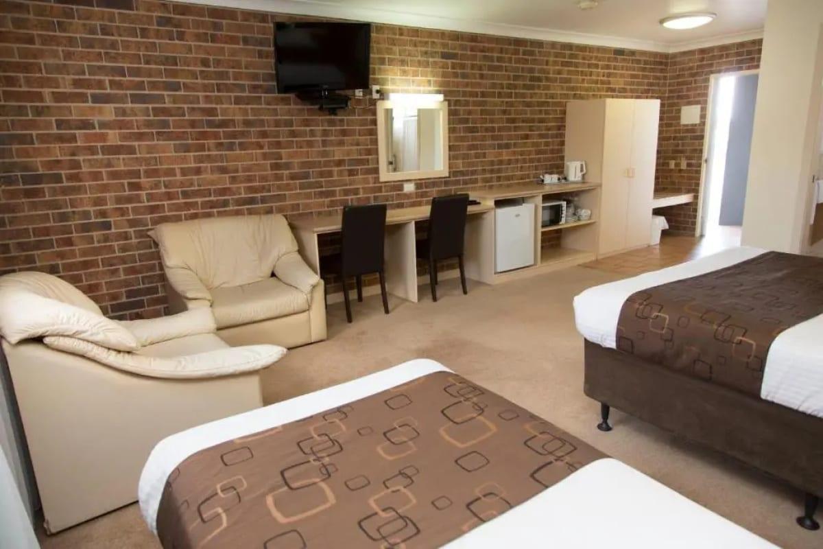 Deluxe family room with brick feature walls, leather armchairs, desk and kitchenette wall