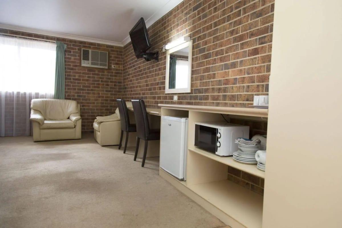 Deluxe kitchenette corner with bar fridge, microwave, crockery and wall-mounted TV