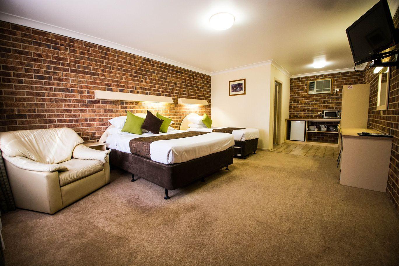 Deluxe room with brick feature wall, queen bed and lounge chairs