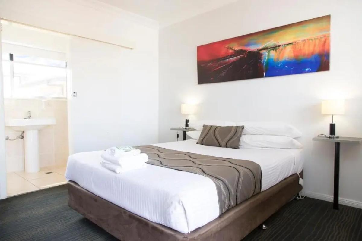Standard room with a neatly made queen bed and ensuite