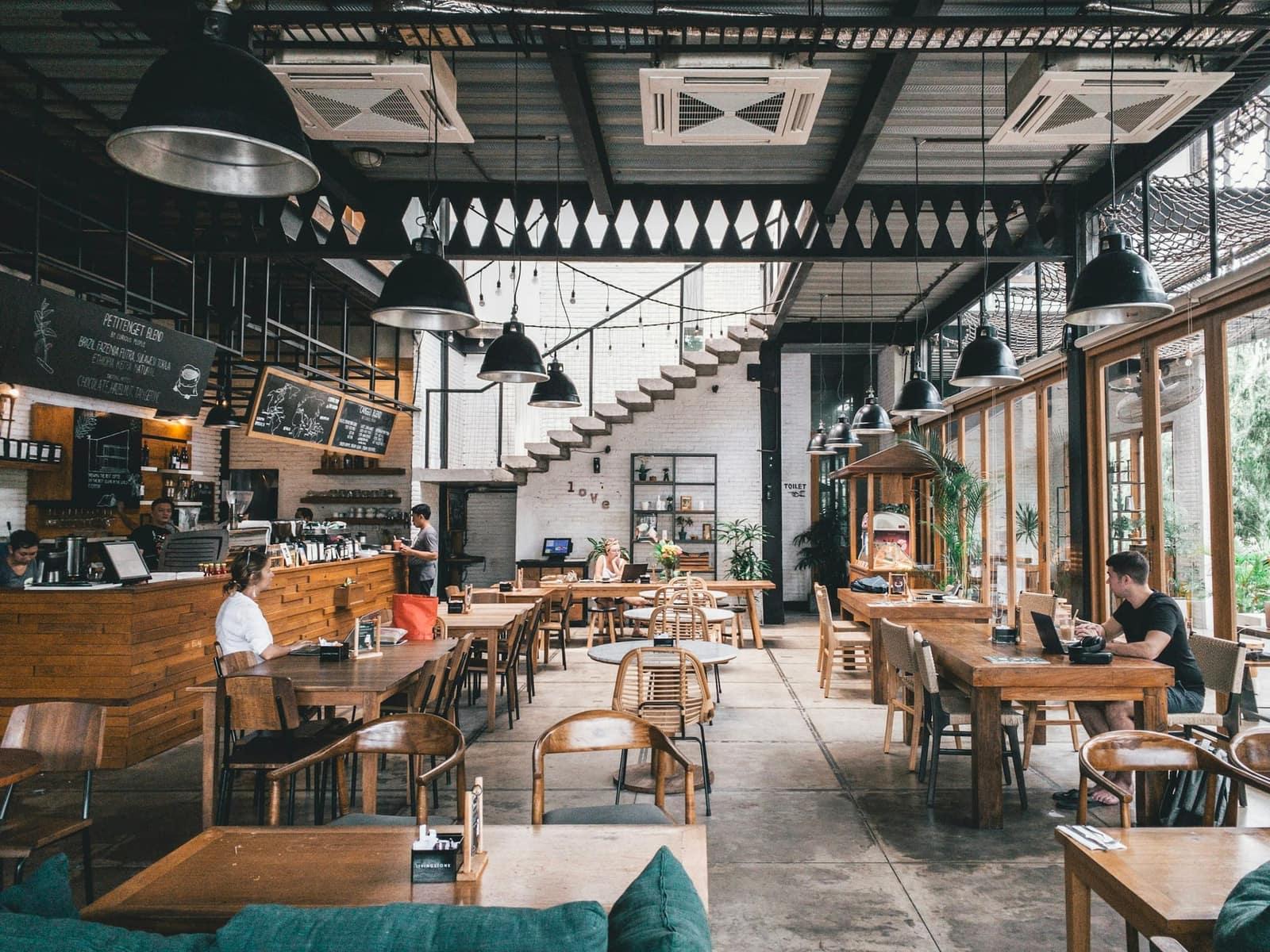 A warm cafe in town, long tables and hanging lamps