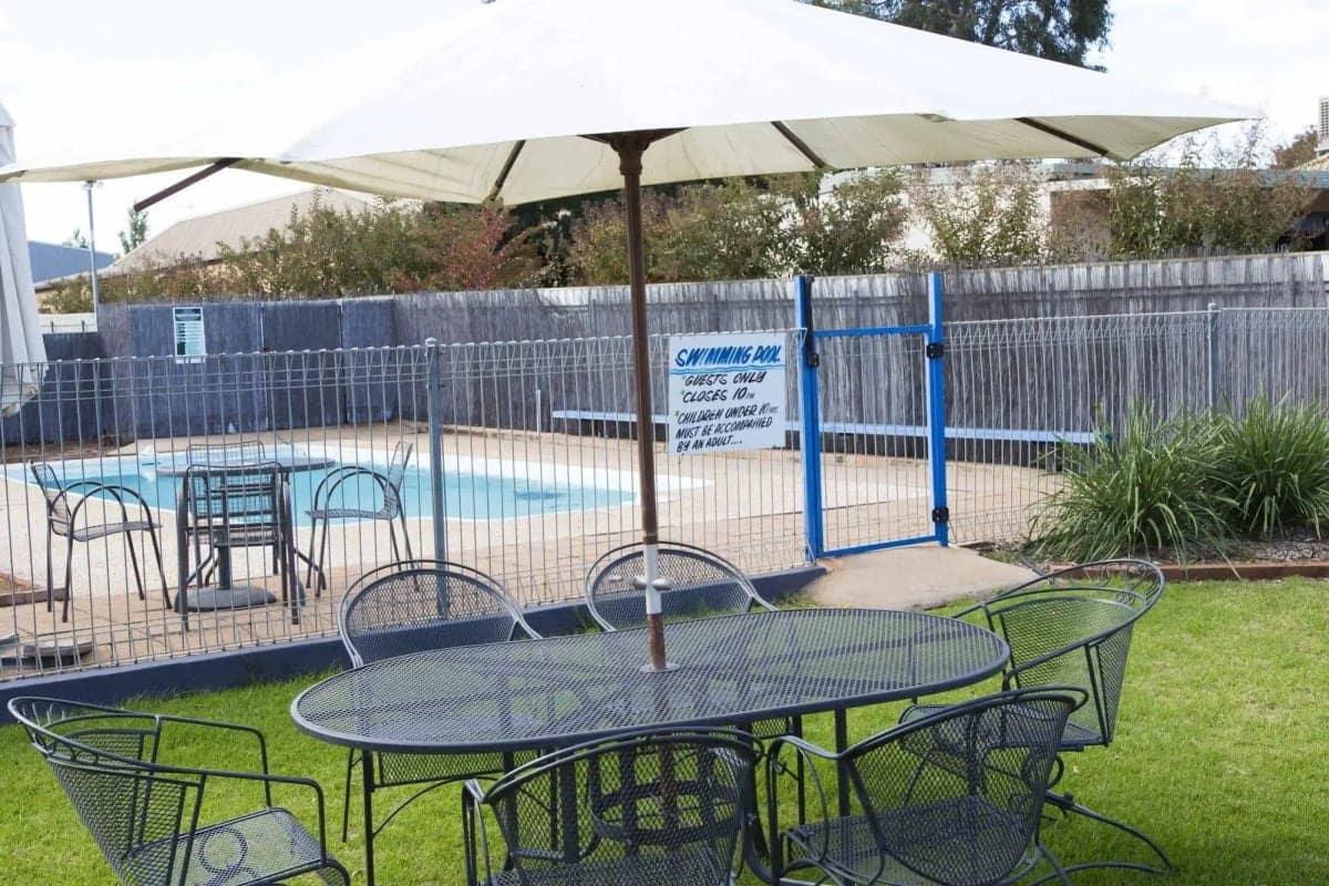The fenced outdoor swimming pool, with an umbrella-shaded table on the lawn beside it